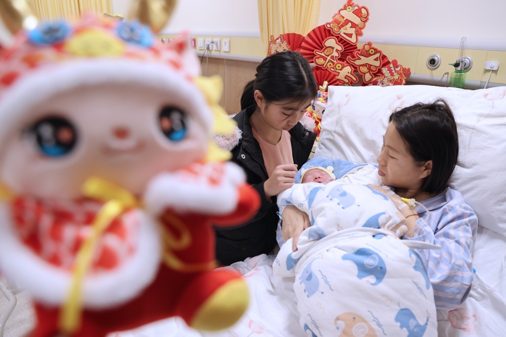 江苏无锡怡和妇产医院产科病区内，一名刚出生的「龙宝宝」和妈妈、姐姐在一起。 新华社