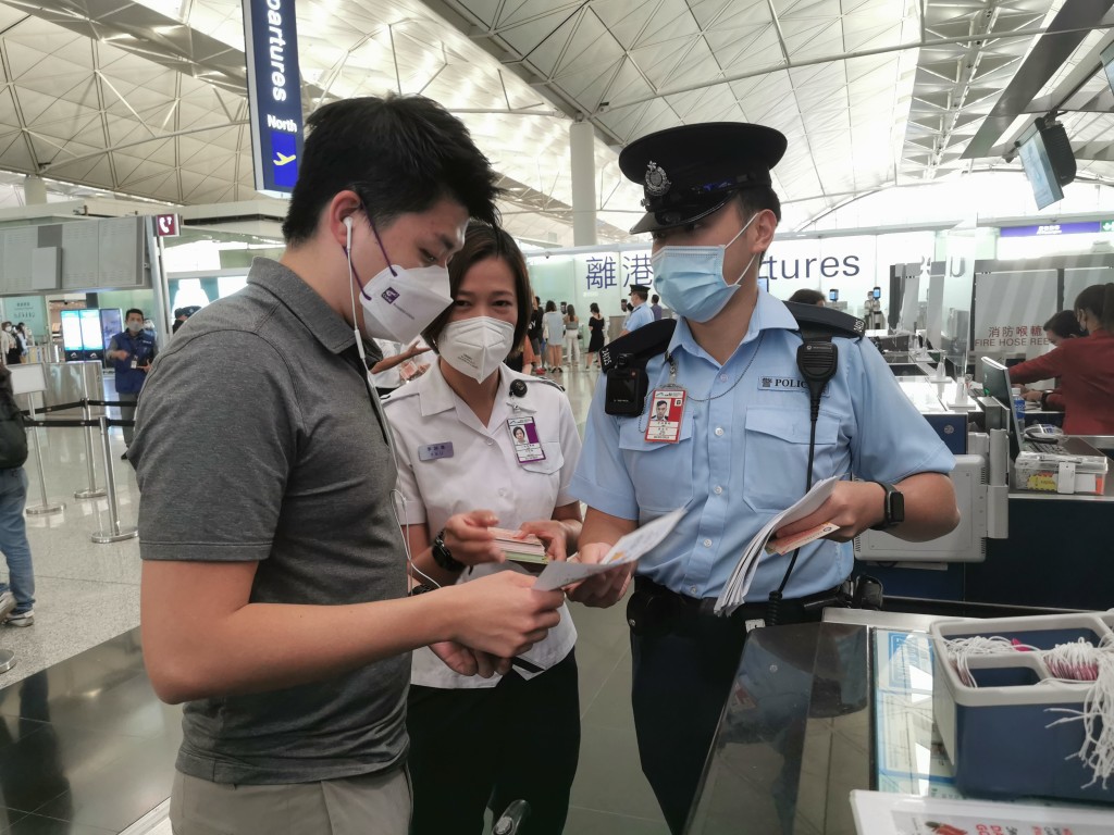 警務處和入境處人員在機場派發宣傳單張，提醒離港旅客小心求職騙案及注意外遊安全。