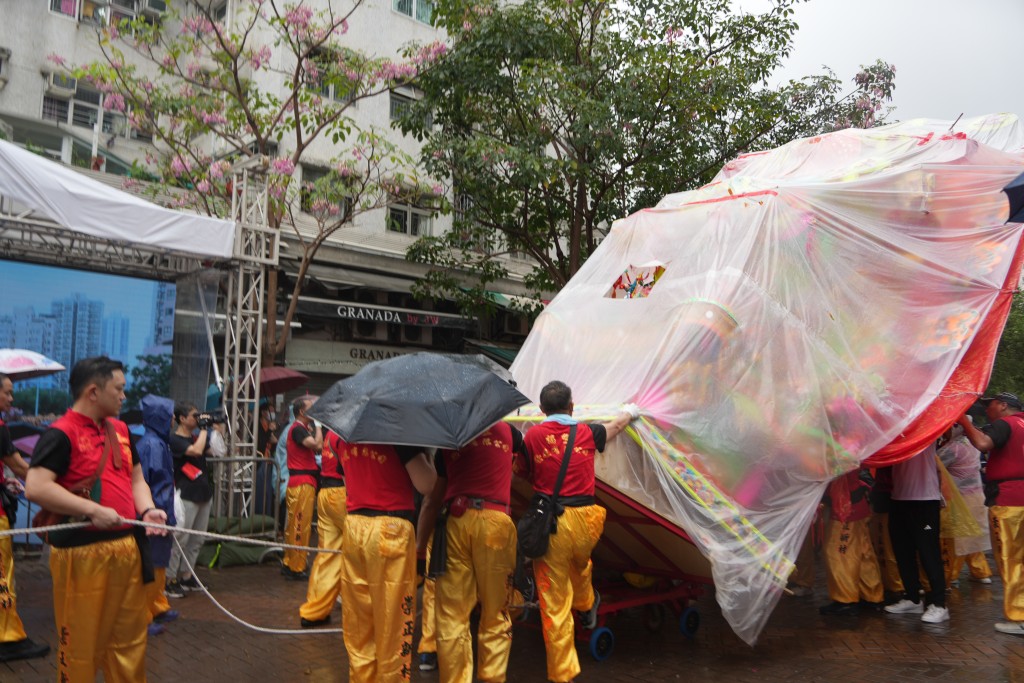 巡游队伍不少人身穿雨衣，纸制花炮亦被被塑胶膜包裹。吴艳玲摄