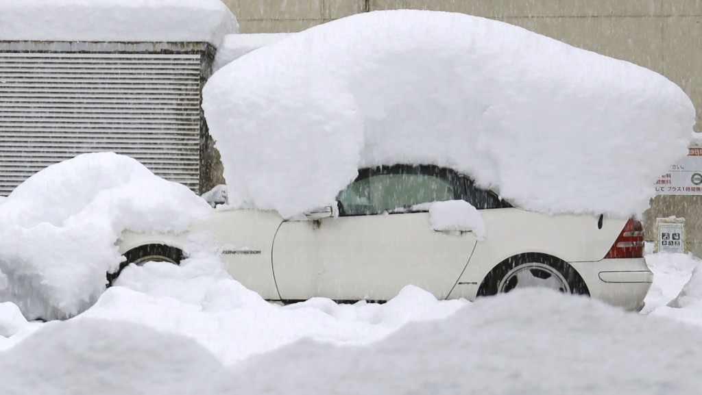 日本北部暴雪,有車輛被重重的積雪壓著。 AP