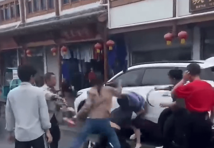 橫間T-恤男被一人推至車旁，其他人則不停施暴。