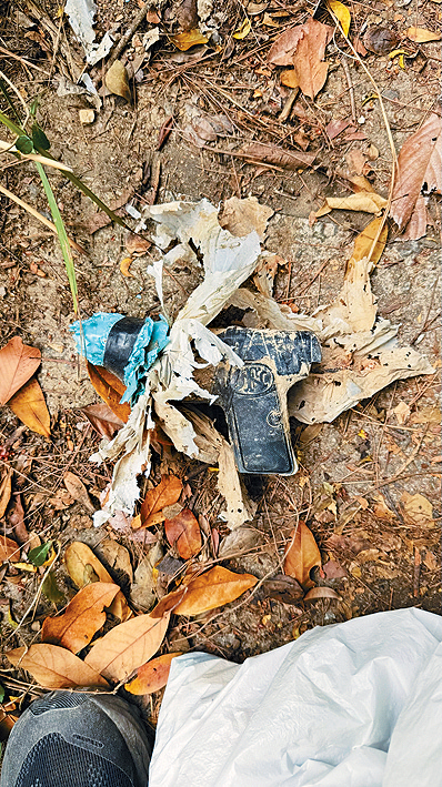 事主在草叢堆發現一支懷疑手槍，槍身沾滿泥土、被膠紙捆綁。