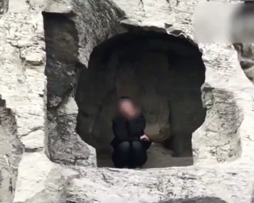 涉事旅客趁機翻越欄杆,爬到洞窟內拍照。片段截圖