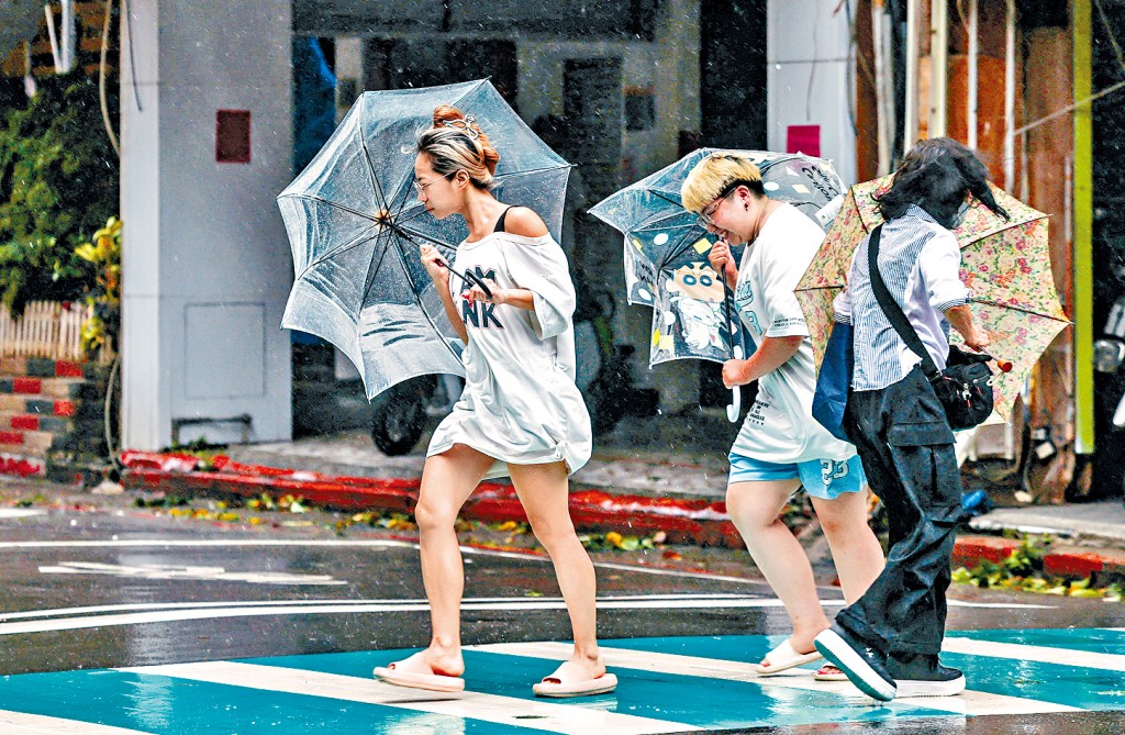 「巴威」來襲，台灣基隆行人撐傘在狂風暴雨中過馬路。
