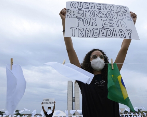巴西逾60萬人感染新冠肺炎後死亡，有民眾舉牌抗議：「誰為慘劇負責？」 （美聯社）

