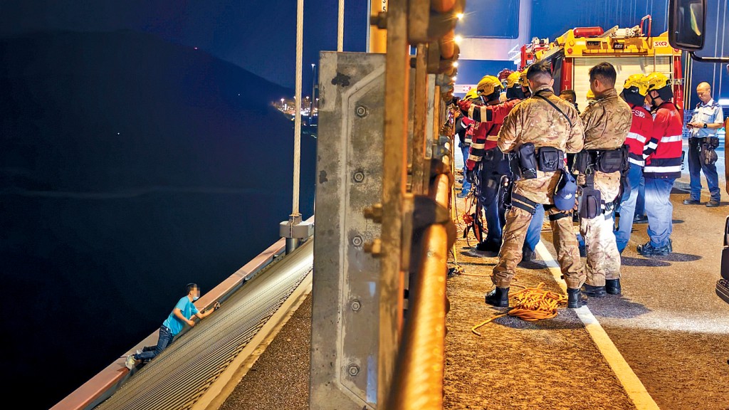 姓董男子在青馬大橋鐵欄外危坐，警方談判專家奉召到場勸喻。 