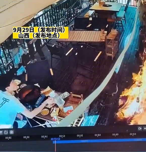 女食客突然起身点燃墙上的芒草装饰引发大火，叫同伴用水救火。影片截图
