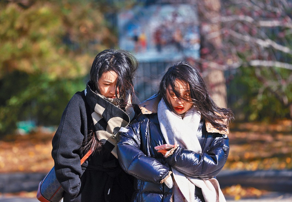 北京降溫，市民昨天在街頭出行。