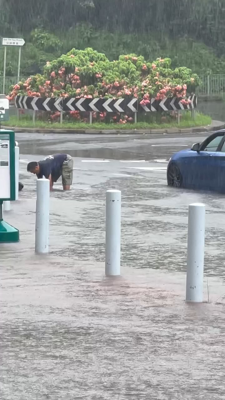 一名中年男子冒着大雨伸手落積水清走垃圾。threads@_.yuching