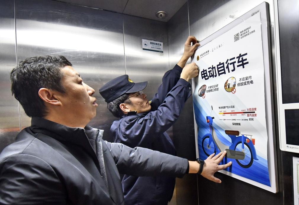 安全生產檢查人員在北京市大興區天宮院街道的居民樓電梯內張貼電動單車安全使用宣傳畫。新華社 安全生產檢查人員在北京市大興區天宮院街道的居民樓電梯內張貼電動單車安全使用宣傳畫。新華社