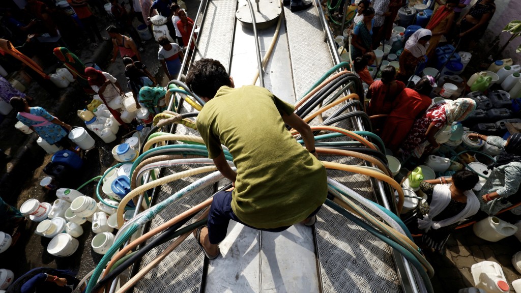新德里居民涌往一輛水車領取飲用水。 路透社
