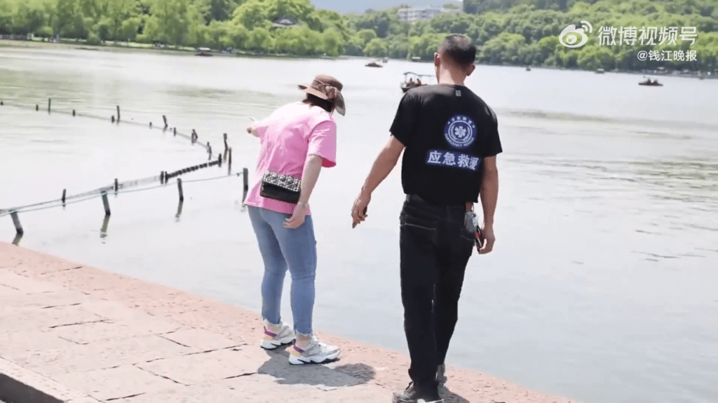 女遊客的手機跌落西湖，找來衣服上寫著「應急救援」的男子幫忙。