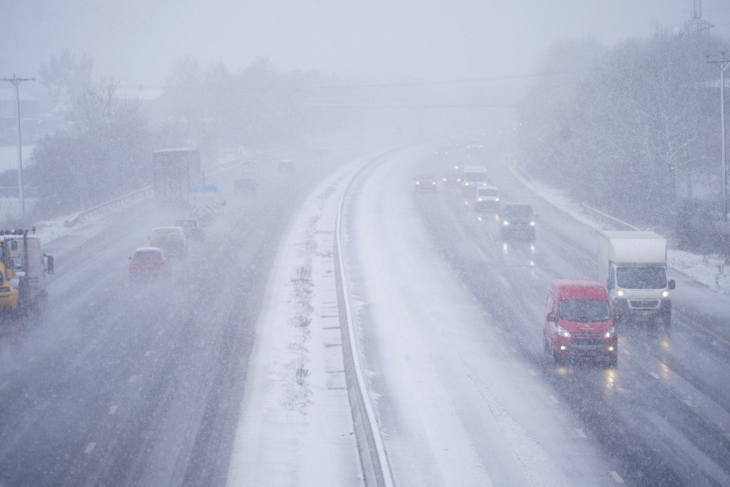 随著北极风暴的加剧，零星的降雪和冰雹阵雨将影响苏格兰的北部海岸，汽车在英格兰汤顿附近的 M5 高速公路上驶过积雪。AP