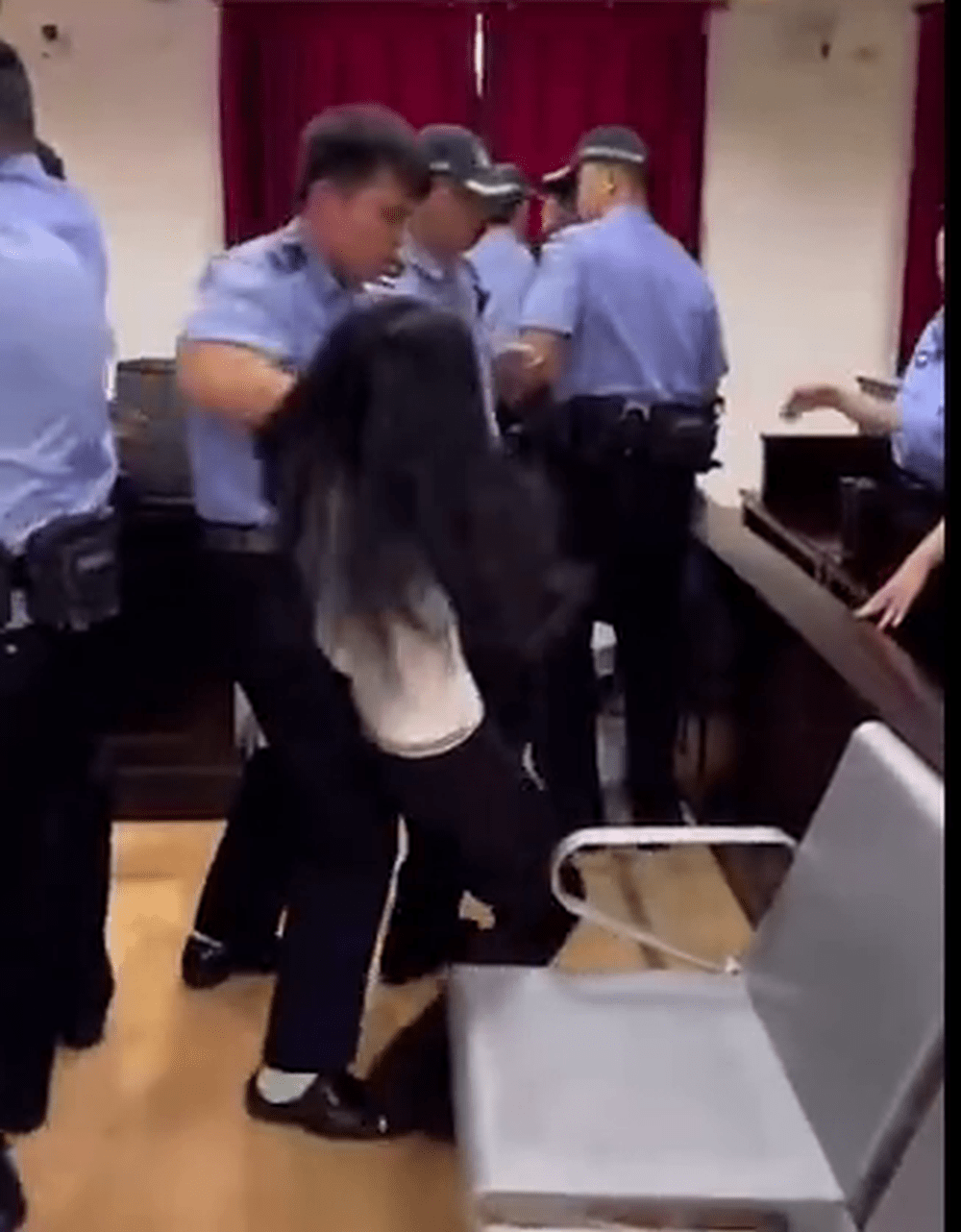 白衫的女律師遭法警強奪手機，拉扯間女律師倒地受傷。