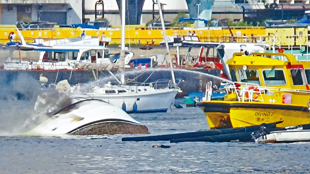 翻沉遊艇死灰復燃,消防員不斷射水滅火。