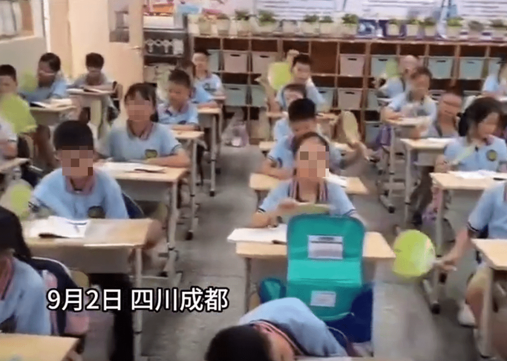 成都一小学学生满头大汗，一直摇著扇子降温。