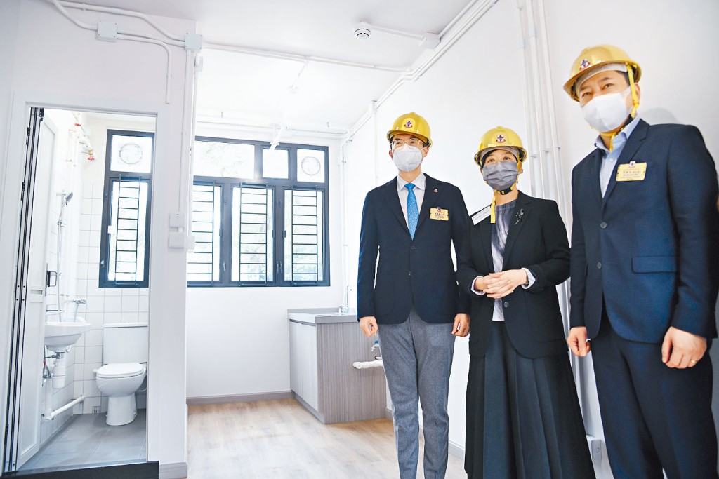 東華三院主席馬清揚（左一）及房屋局局長何永賢（中）視察過渡屋。 