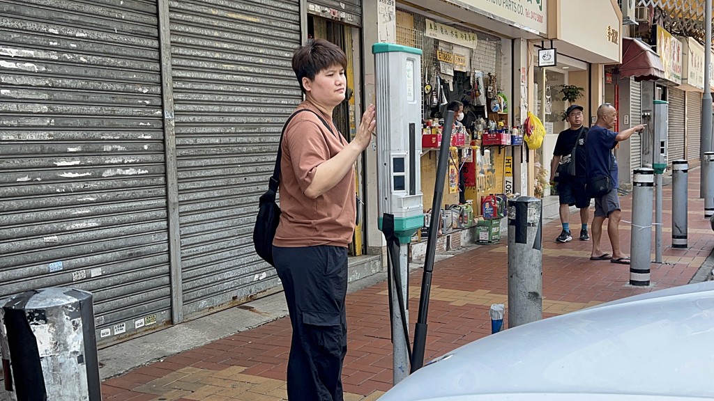 車房老闆娘替店前車輛入錶。楊偉亨攝