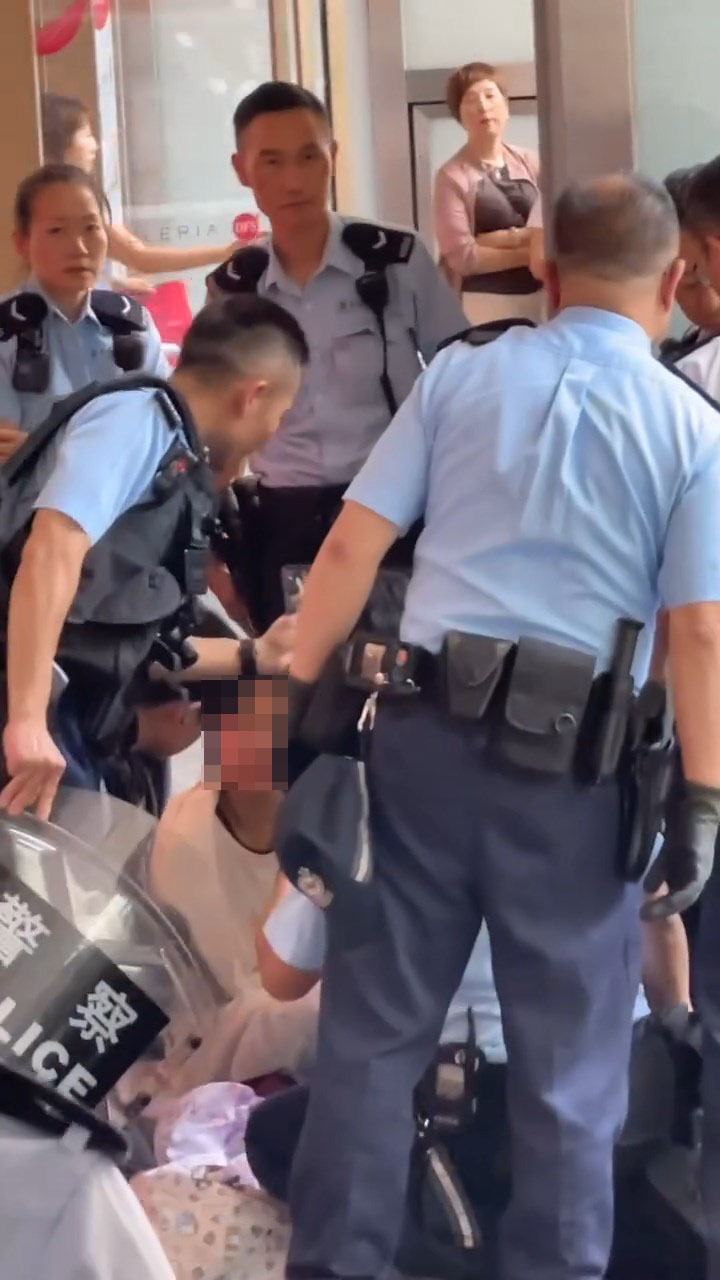 女子被制服後一度坐在地上,雙手被鎖上手銬。 女子被制服後一度坐在地上,雙手被鎖上手銬。