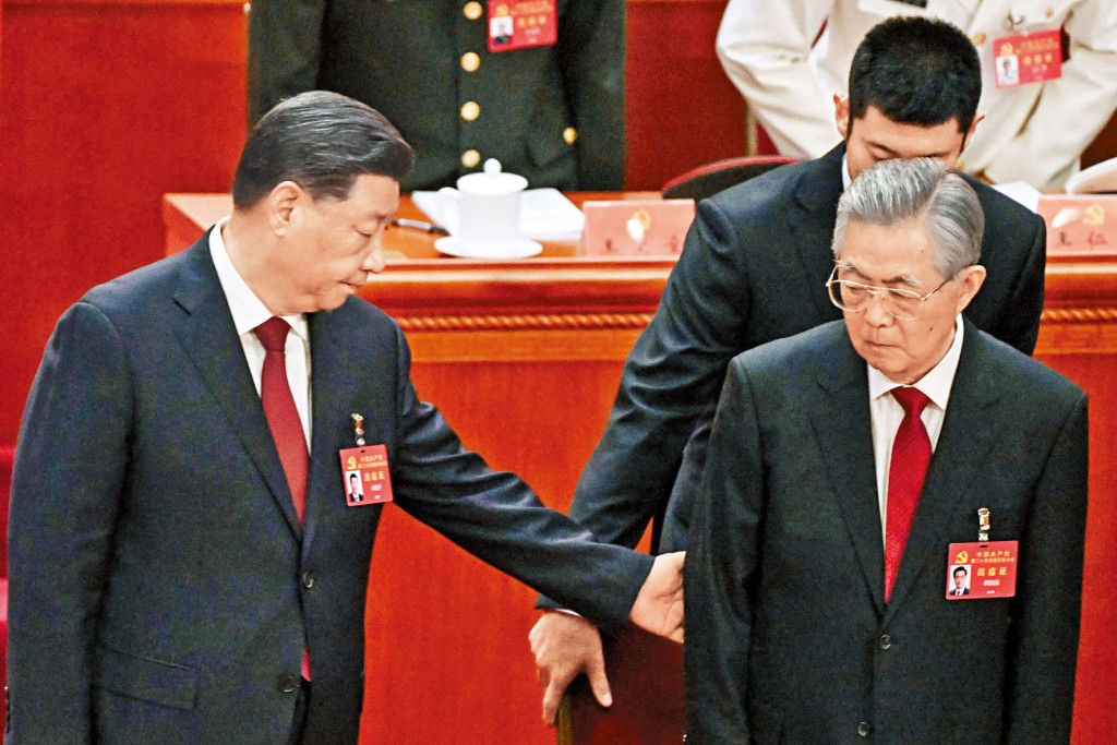 胡錦濤(右)在工作人員攙扶下就座。習近平在旁幫忙。