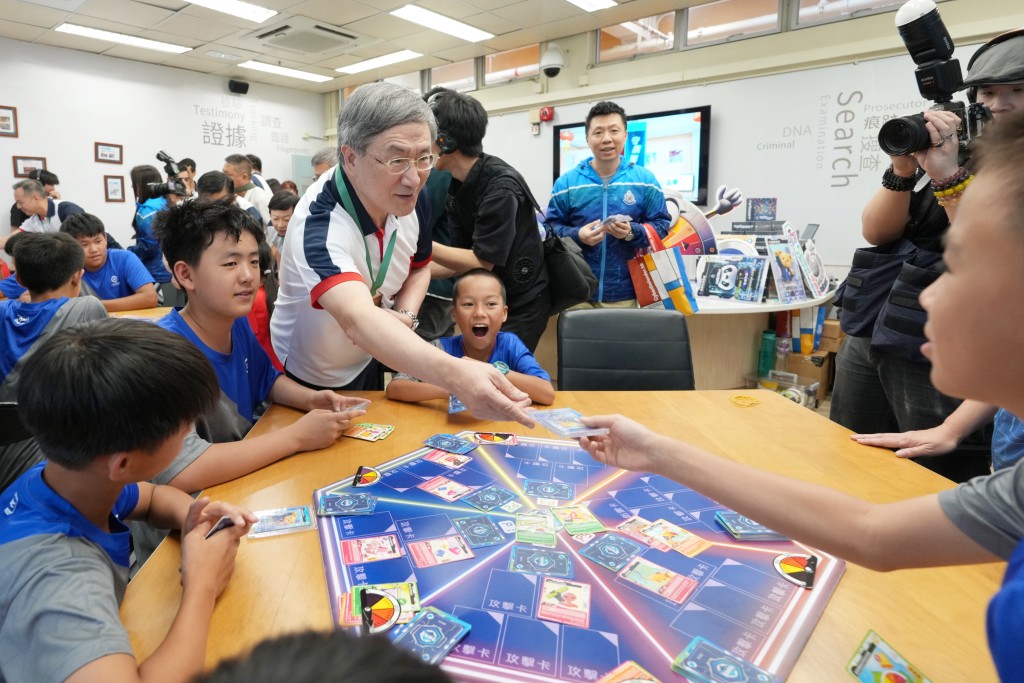 政務司副司長卓永興（左三）與少訊會員參與「守網聯盟遊戲卡」防騙遊戲，宣傳防騙信息。