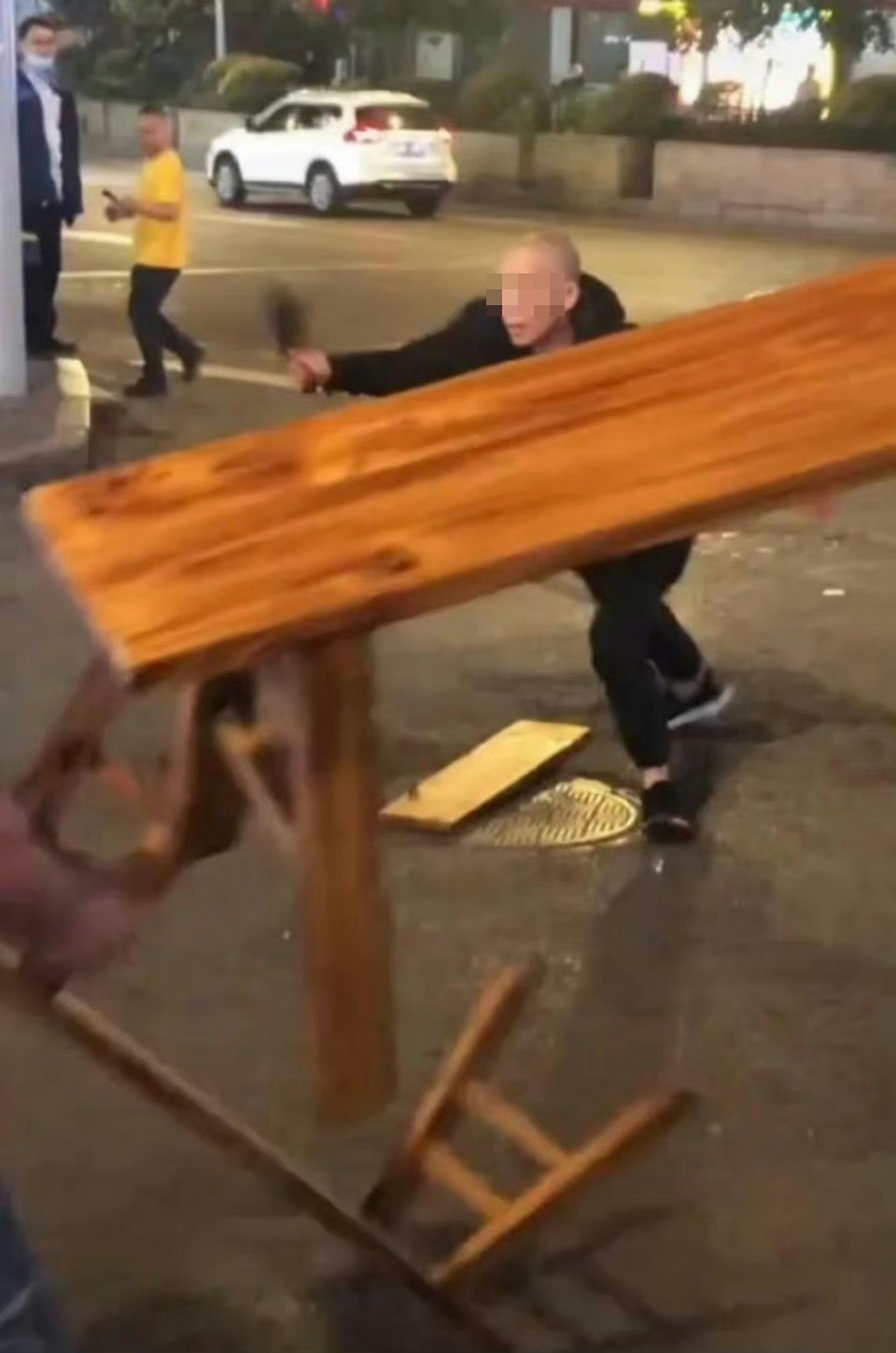 多名民眾手持木板櫈與男子對峙，有人企圖上前將他制服。微博圖