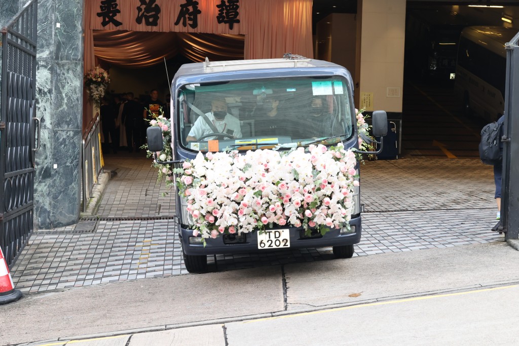 丈夫Chris手持亡妻遺照步上靈車。