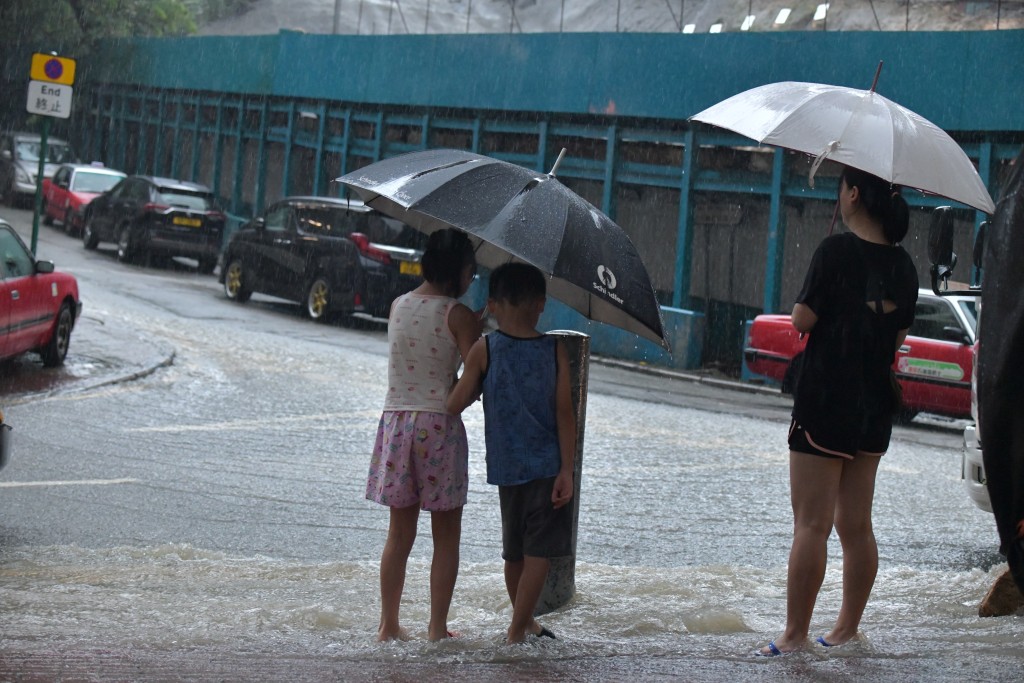 居民撑起雨伞涧水而行。禇乐琪摄