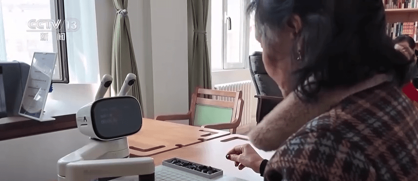 老人与机械人下棋。