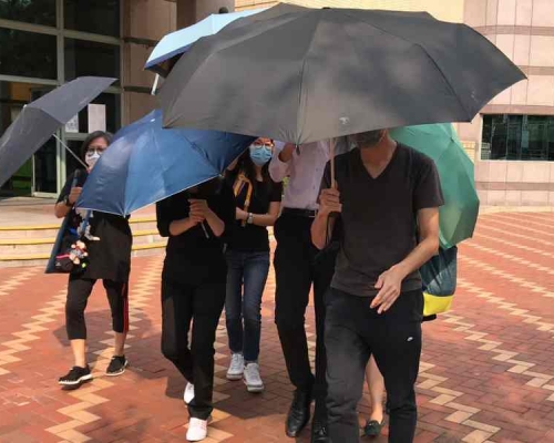 被告羅曉鋒(白恤衫者)在傘陣保護下離開法院。葉君怡攝
