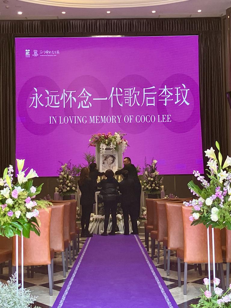 李玟安葬于武汉石门峰纪念公园，​工作人员在李思林（左一）及李秋林（中）指示下摆放好李玟的遗照。