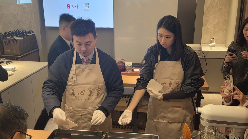 立法會議員梁進（左）及江旻憓（右）在廚師指導下，製作並品嚐黑芝麻卷。趙克平攝