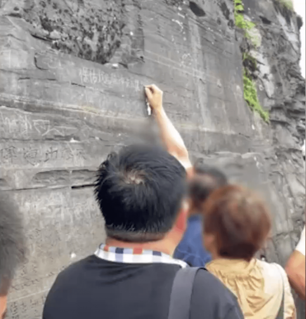 在贵州梵净山景区，有游客拍摄风景时意外外到有人在岩壁上刻字。
