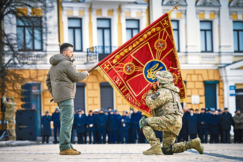 乌克兰总统泽连斯基昨日在纪念乌战一周年活动中举起一面军旗，一名军官亲吻旗帜。