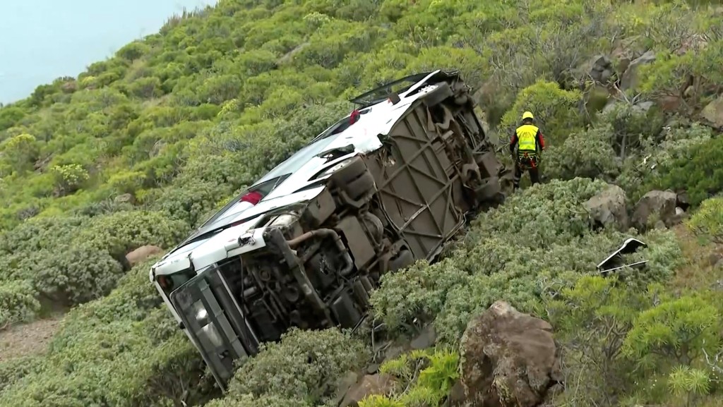 這輛載著28人的白色巴士從公路墮落山坡。路透社