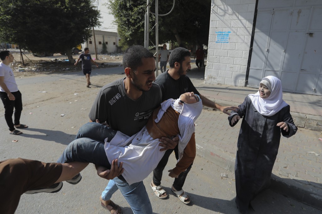 以军空袭加沙城，一名女孩受伤，被民众抱走。美联社