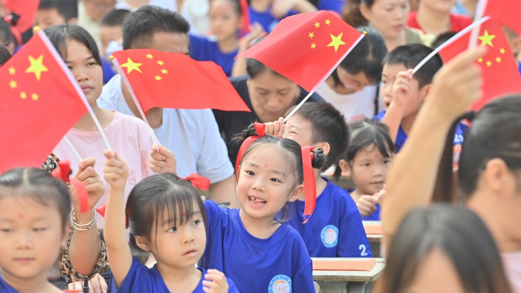 廣西梧州市小學生在主題活動中揮舞國旗。新華社