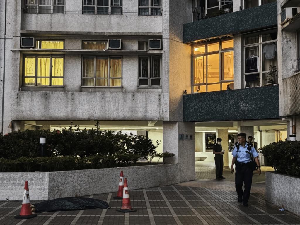 警方用綠色布將遺體掩蓋，並在現場調查男子墮樓原因及經過。黎志偉攝
