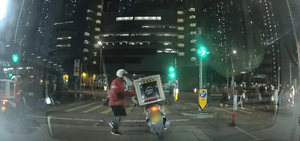 协助婆婆过完马路，Pizza Hut 哥哥冲返电自行车，此时交通灯转绿灯。网片截图