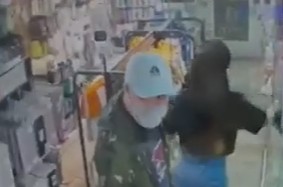 男賊在店東張西望，然後叫女店員在櫥窗取出Samsung手機。CCTV截圖