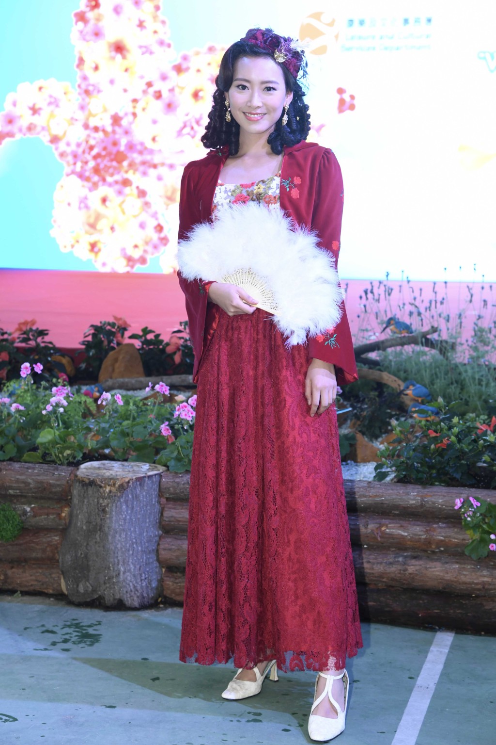 香港小姐陳靜堯身穿西式宮廷服出席維多利亞公園支持2019年香港花卉展覽“大紅花說願”攝影比賽活動。