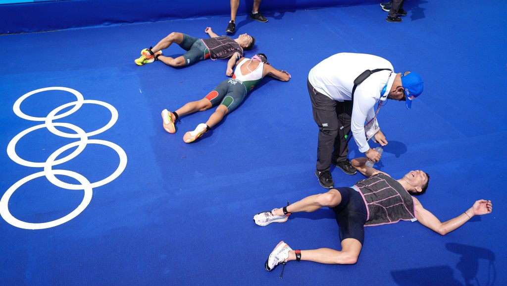 三项铁人参加者完成赛事后倒在地上休息。 美联社