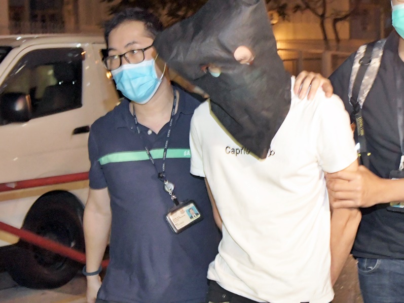 黃鈞華(蒙頭者)被警方押解。資料圖片