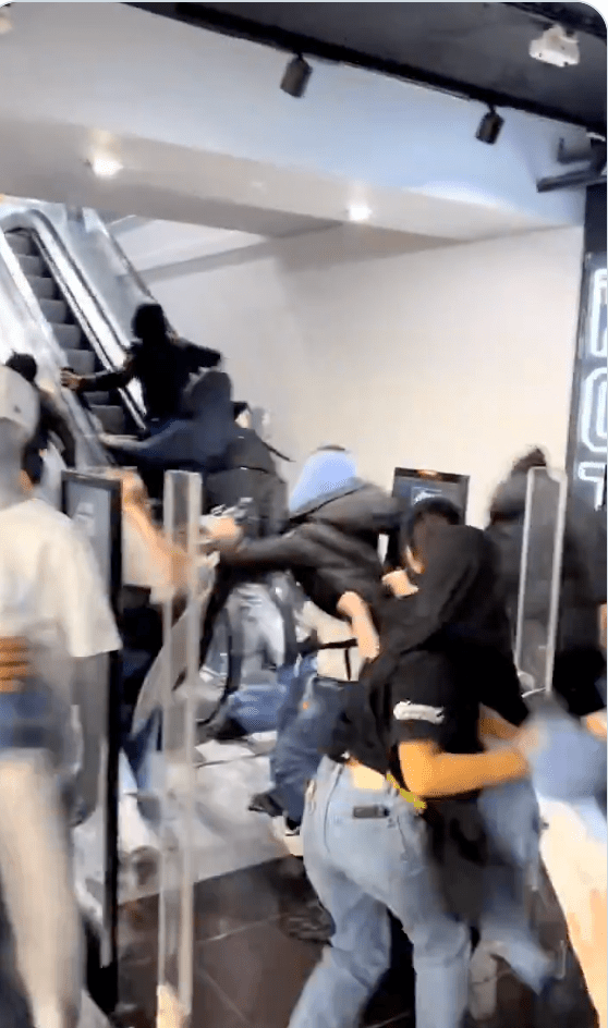 當歹徒企圖沿扶手電梯逃跑時，女店員們在移動的電梯上與他們發生肢體衝突，奮力扯下對方手中的衣物。