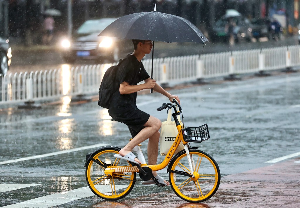 北京持续降雨市民冒雨出行。中新社