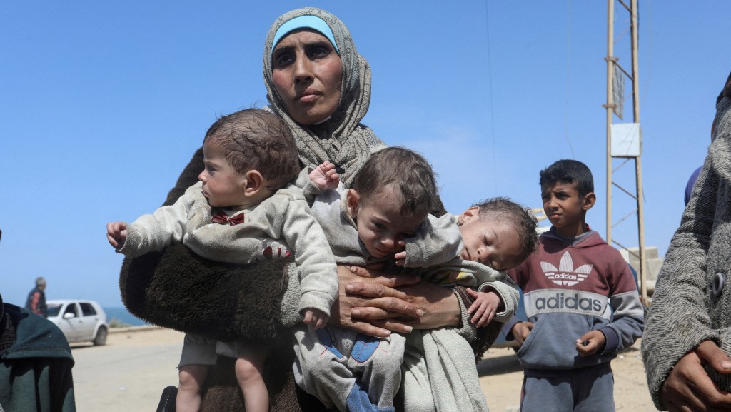 一名巴勒斯坦女子抱着三胞胎，從加沙中部逃往南部。 路透社