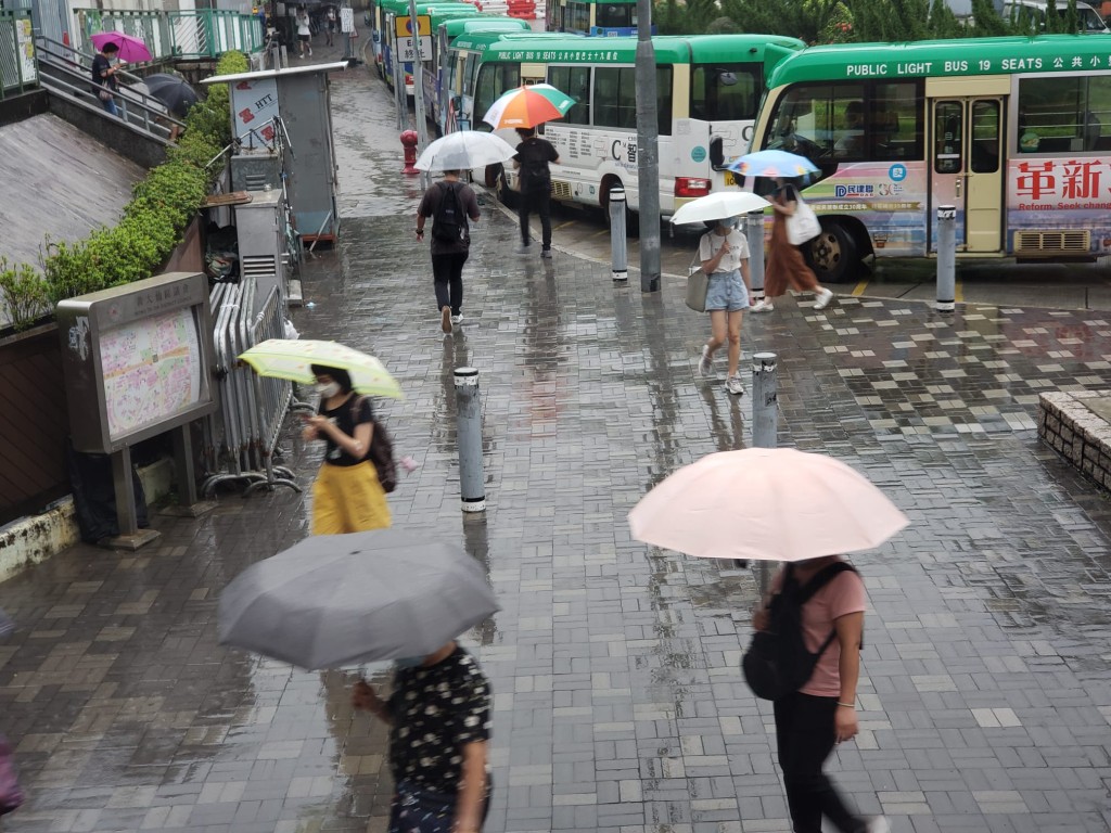 行人撐起雨傘。