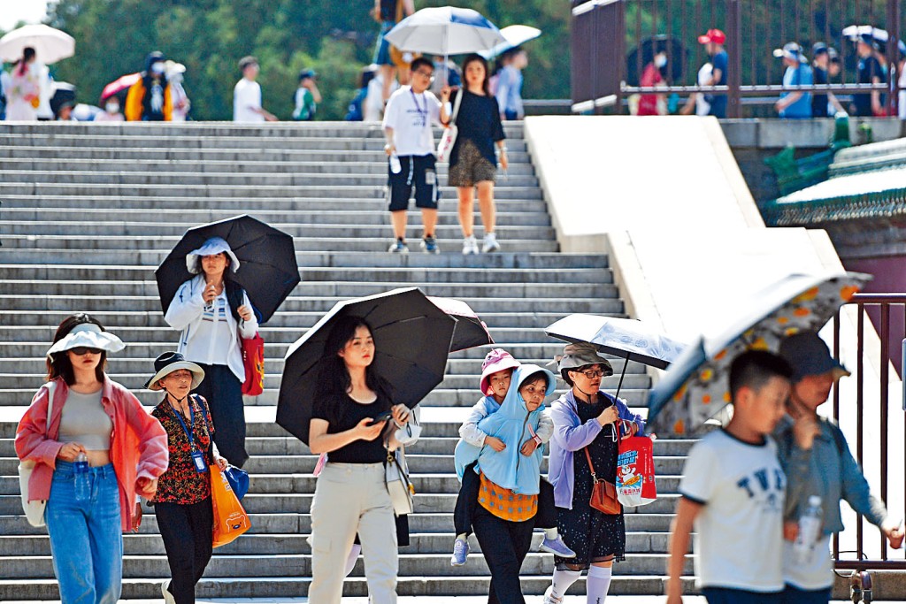 北京民众撑伞抵挡强烈的阳光。