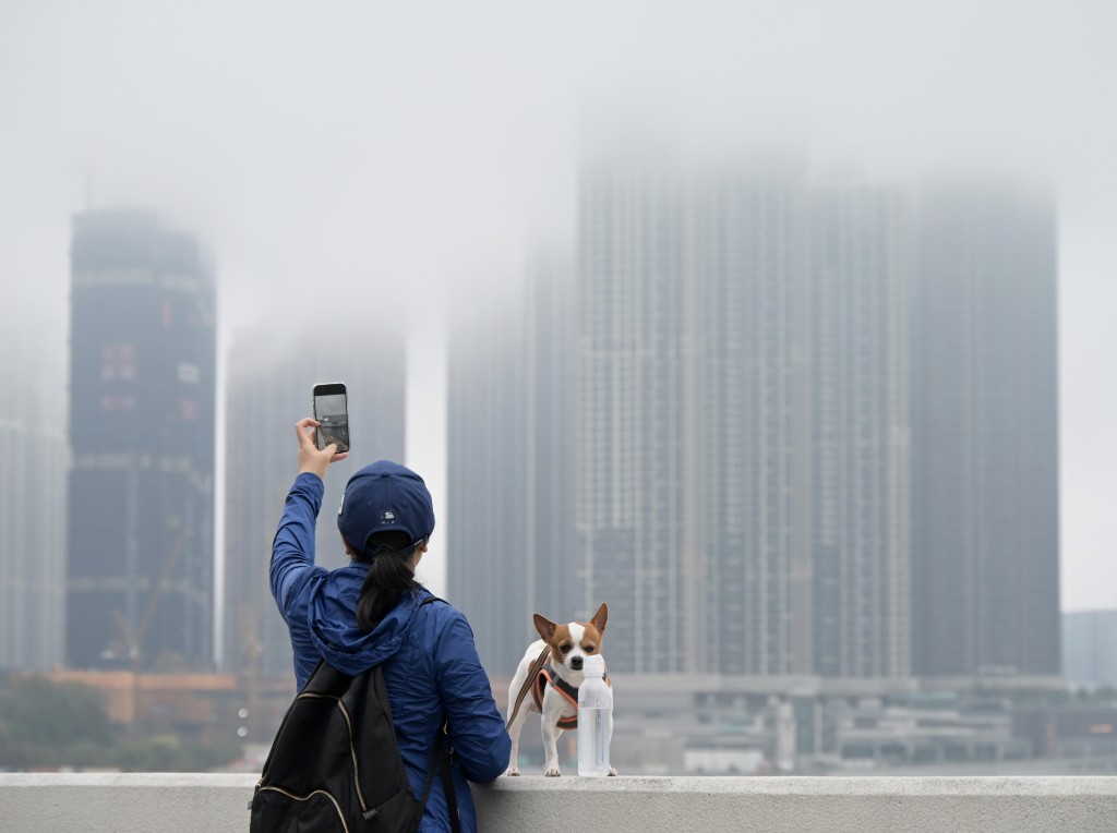 市民举机拍摄云雾中的大厦。 苏正谦摄