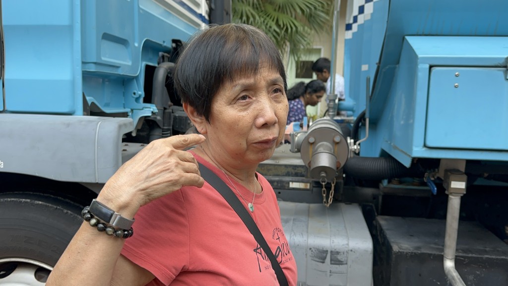 陳女士到水車載水給女兒梳洗返工。梁國峰攝